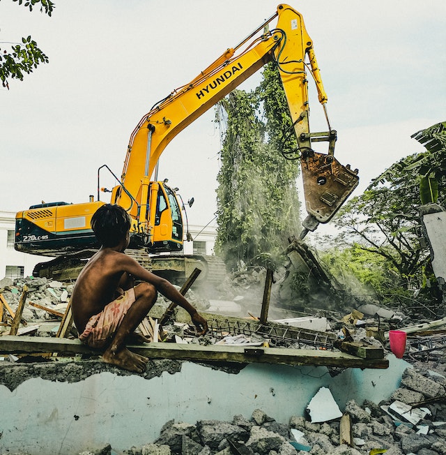 A tractor working on site and a homeless boy watching